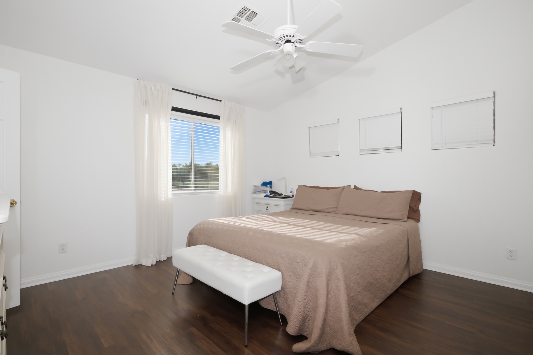 Spacious primary bedroom with warm flooring and natural light
